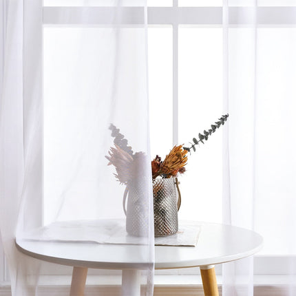 Doorschijnend vitrage gordijn met metalen ringen.