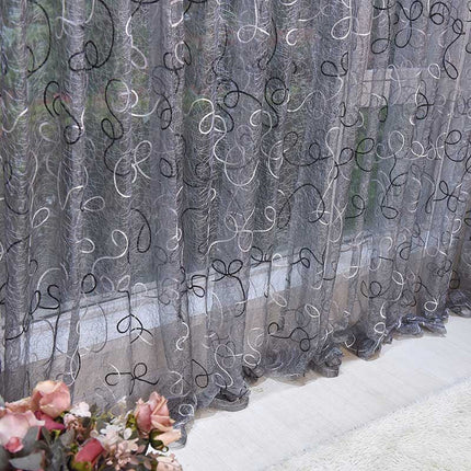 Grijze vitrage met geborduurd krulpatroon