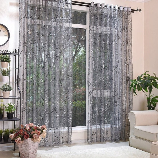 Grijze vitrage met geborduurd krulpatroon