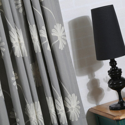 Grijs gordijn met geborduurde madeliefjes